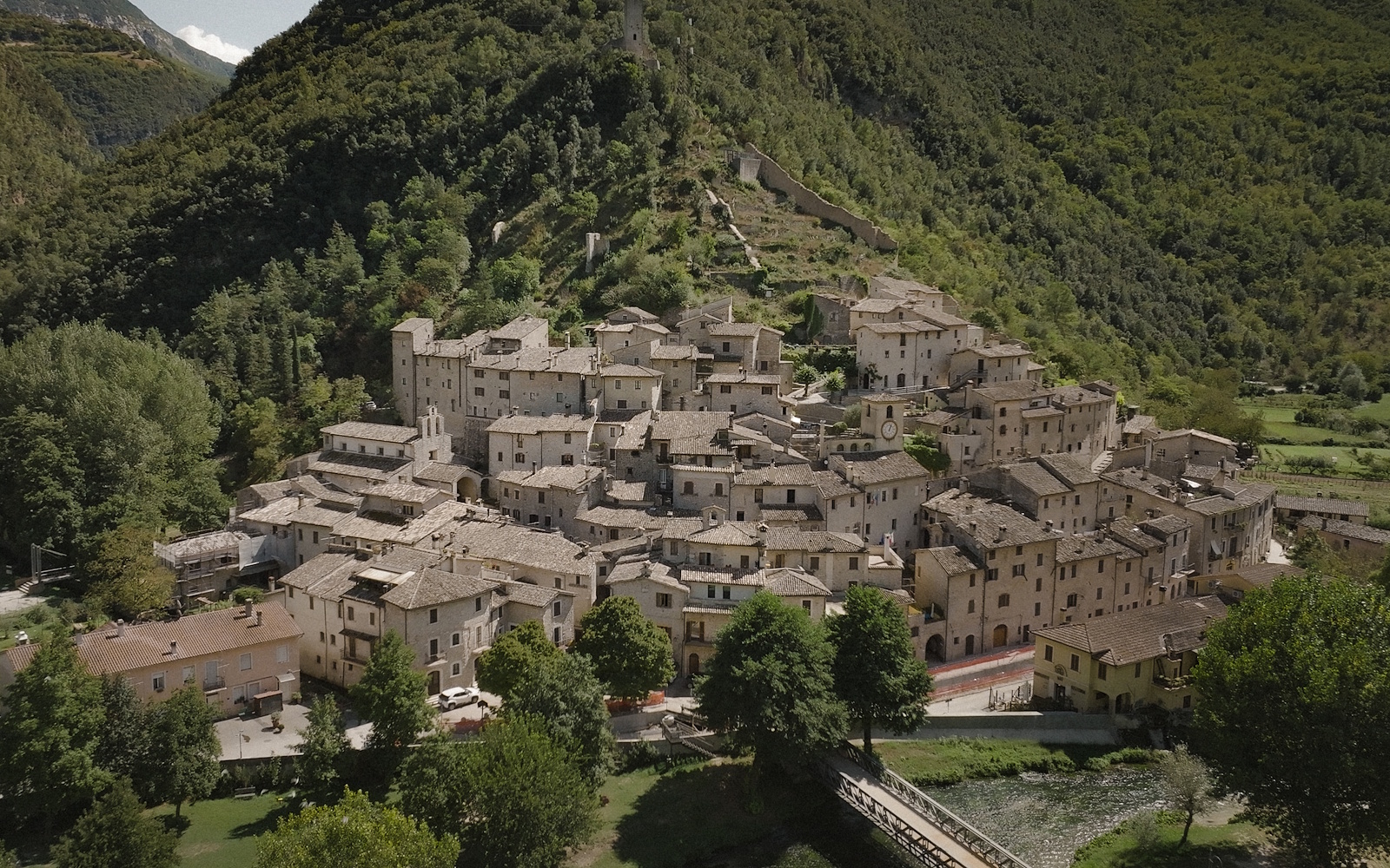  Aerial view of Scheggino, with stone houses and a medieval defensive wall, nestled in the green Valnerina valley. 