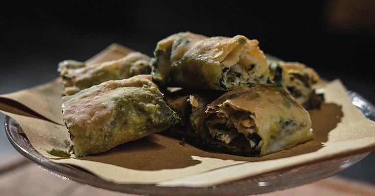 Close-up of fojata, a rolled savoury pie filled with wild greens, served on baking paper.