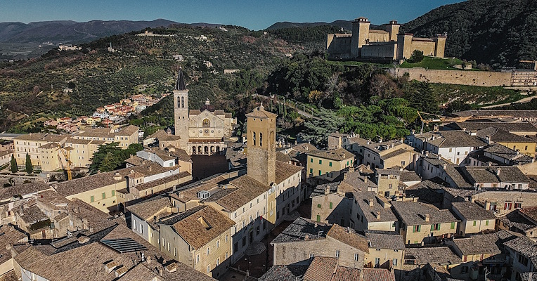 Panoramic view of Spoleto with the Cathedral, the Rocca Albornoziana and historic rooftops nestled among Umbrian hills.