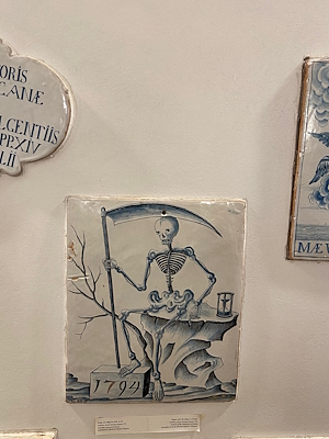 Tile from 1794 depicting a skeleton with scythe and hourglass, preserved in Deruta.