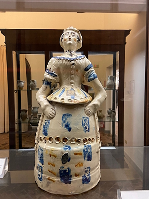 Polychrome ceramic sculpture representing a female figure in dress, displayed at the Deruta museum.