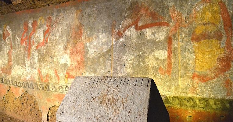 Urna con iscrizione posta davanti alla pittura parietale policroma della Tomba degli Hescanas