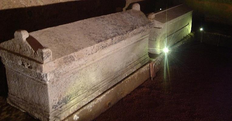 Intérieur de la tombe des Hescanas avec sarcophages et urnes en pierre posés sur la banquette le long des murs