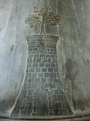 Bas-relief on a bronze bell depicting a stone tower topped with a stylized olive tree