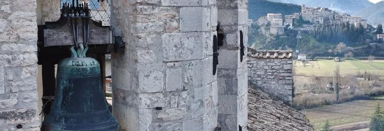 Bronze bell in a bell tower, with a medieval castle in the background 