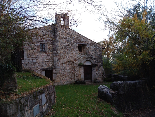 Ancient stone church nestled in autumn greenery, with rustic architecture and a bell gable.