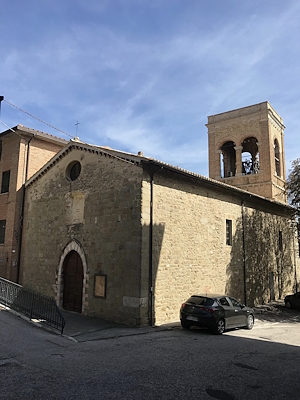 View of the Church of Sant’Agostino in Gualdo Cattaneo, with its stone façade and bell tower standing out against the sky.