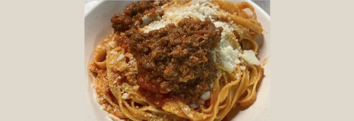 Plate of fresh tagliatelle served with goose ragu and a sprinkling of grated cheese.