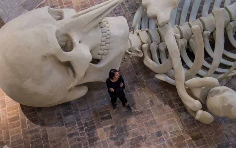  Giant skeleton installed in a deconsecrated church, surrounded by soft lighting and brick architecture 