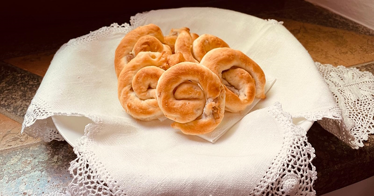 Assiette de lumachelle d’Orvieto en forme d’escargot, disposées sur une serviette blanche en dentelle posée sur un rebord en pierre.