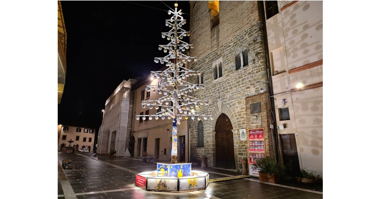 Illuminated ceramic Christmas tree in the square of Deruta, in front of historic buildings on a winter evening.