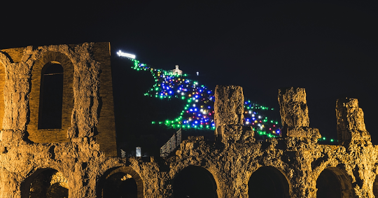  The illuminated ruins of the Roman Theatre of Gubbio in the foreground, with the bright Christmas Tree on Mount Ingino lit by hundreds of colourful lights. 