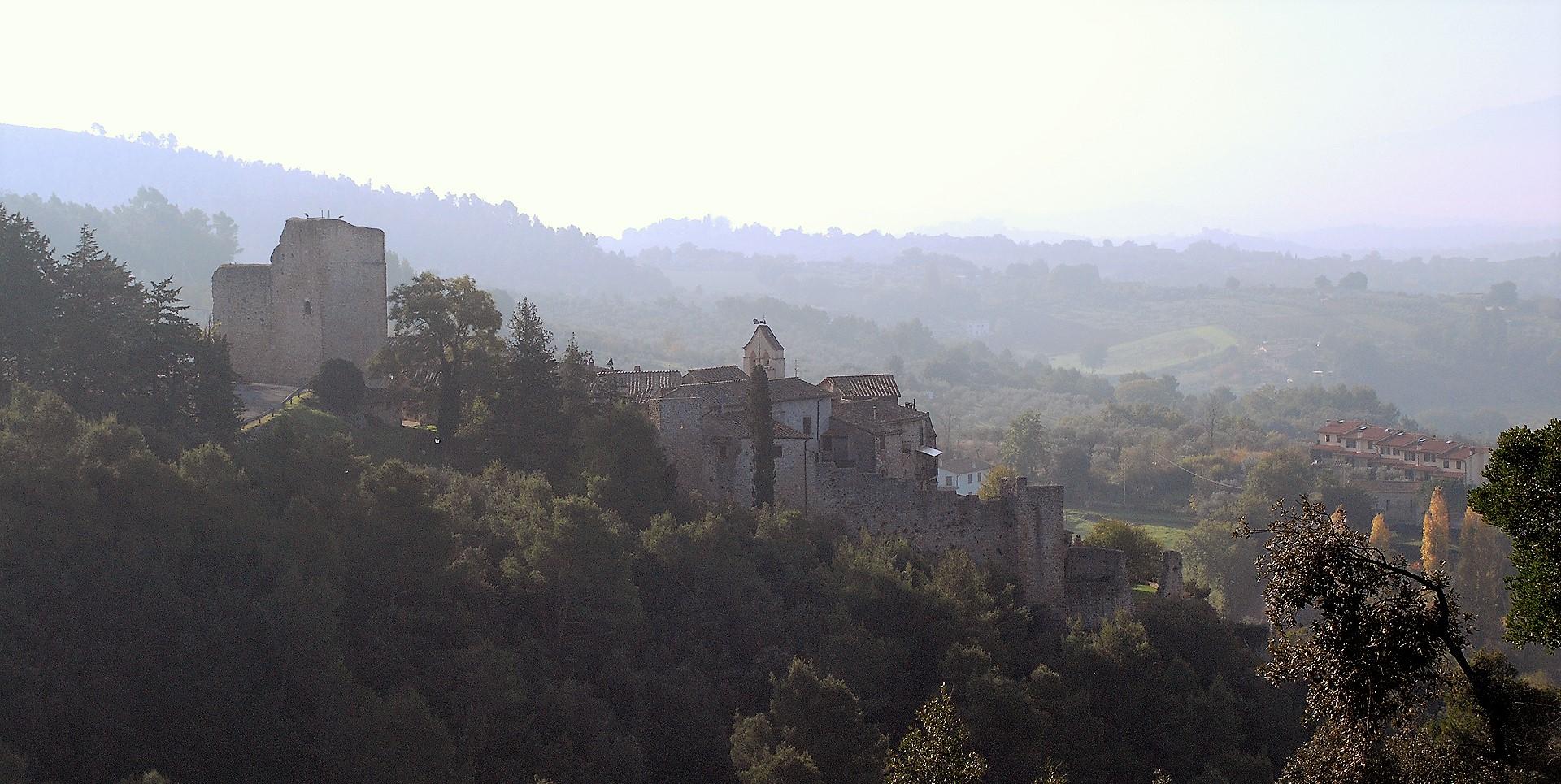 View of the Castle of Poggio di Otricoli, with stone walls and tower, set in a hilly landscape.