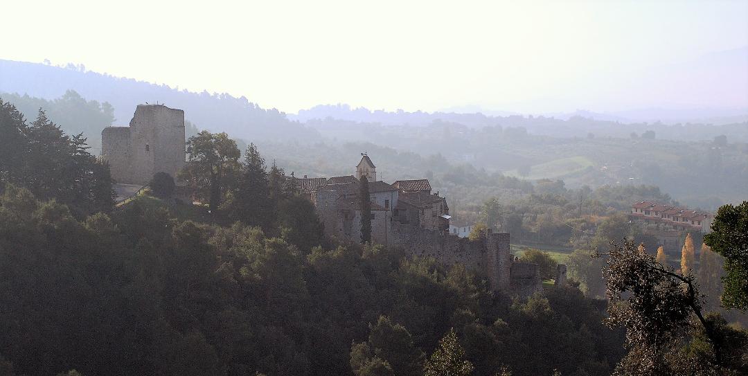 Ansicht der Burg von Poggio di Otricoli mit Steinmauern und Turm in hügeliger Landschaft.