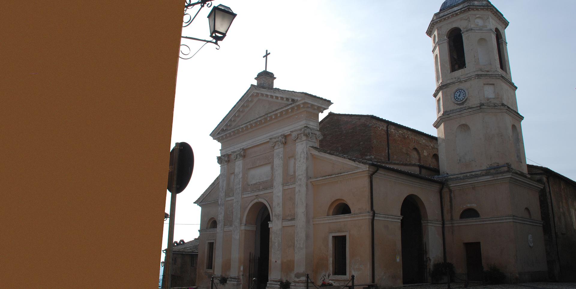 Side view of the Collegiata with classical façade and bell tower, overlooking a village square.