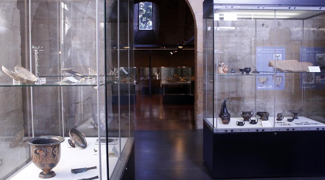 An exhibition room with showcases containing various archaeological artifacts, particularly glossy black bucchero ceramic objects.
