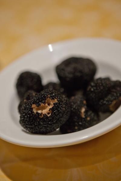 Tartufo nero su un piatto bianco, con una superficie granulosa e sezioni aperte che rivelano l'interno chiaro.