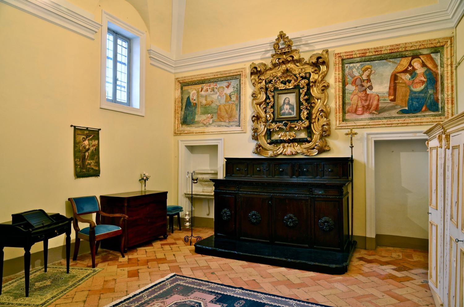 Interior room with Renaissance frescoes, wooden furniture, and a gilded frame in the Church of Madonna della Bianca