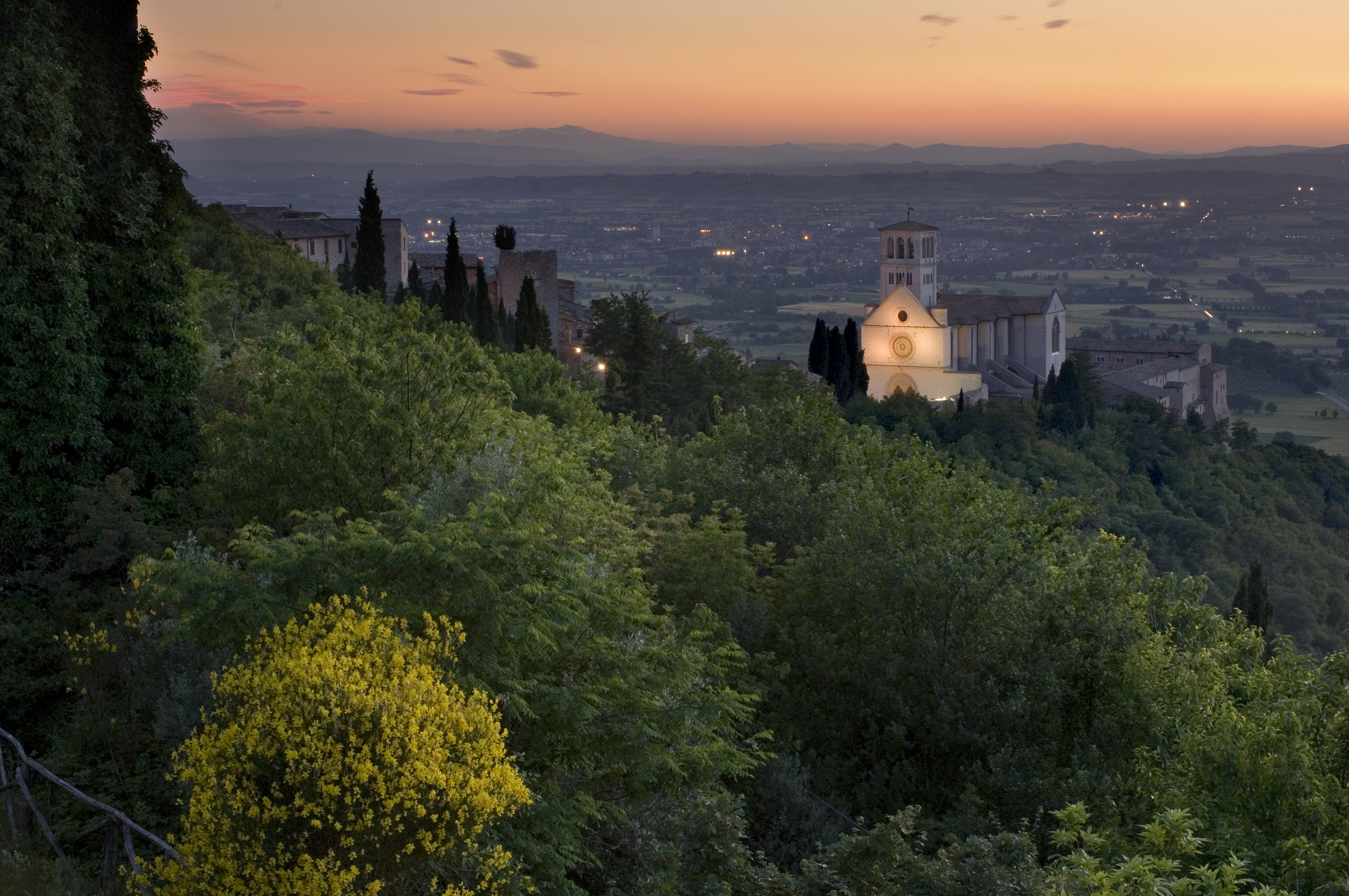 Tramonto sulla città di Assisi, con una splendida vista della Basilica di San Francesco illuminata che domina il panorama.