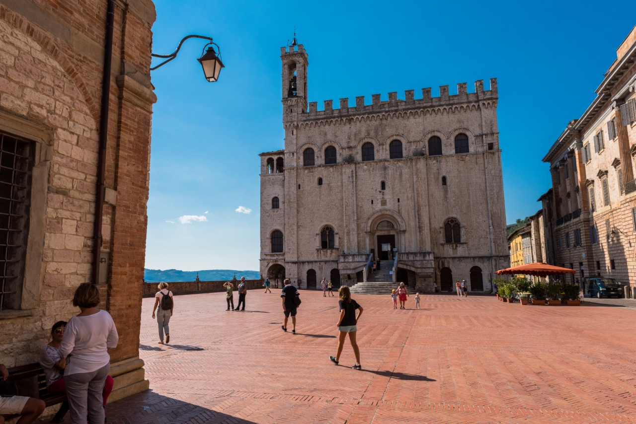 Piazza Grande in Gubbio with the Palazzo dei Consoli and people walking in the square