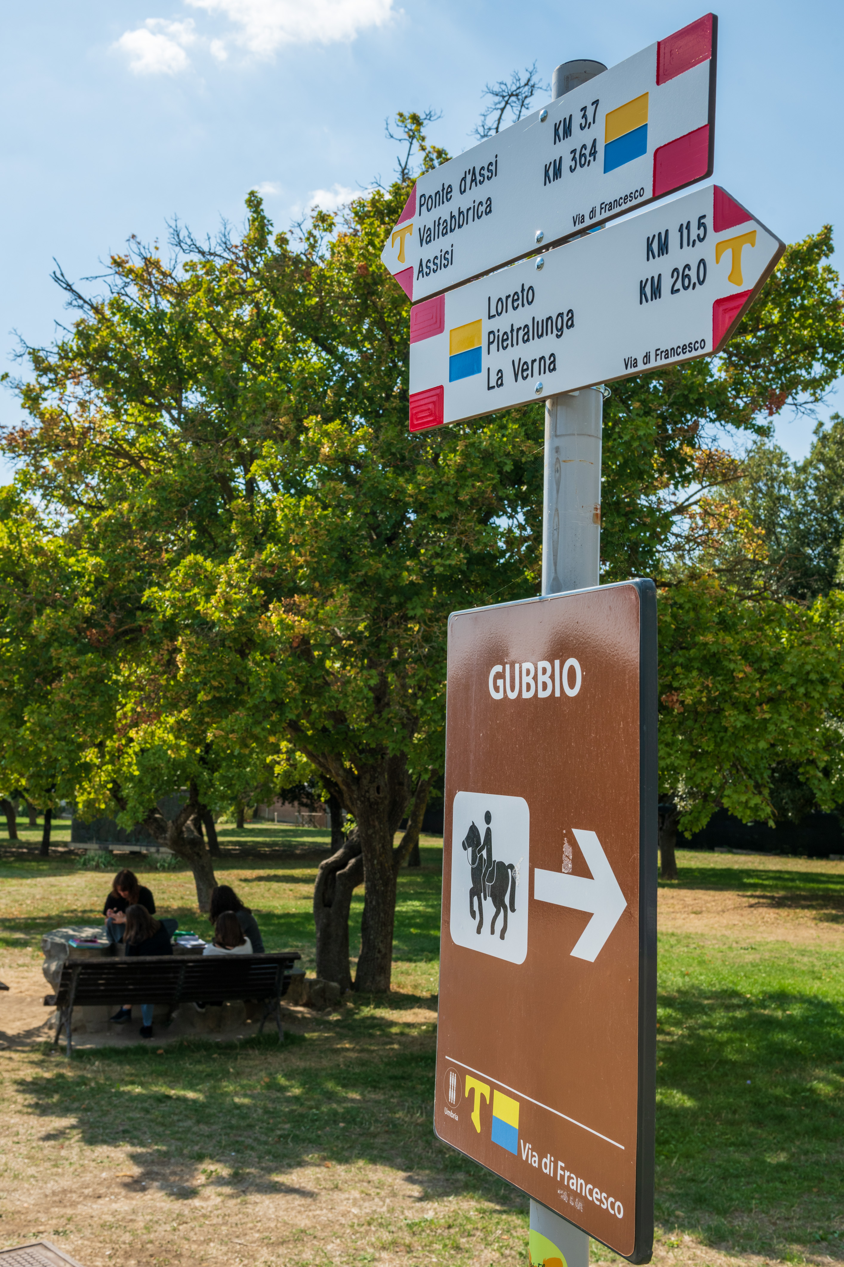 Via di Francesco signposts in Gubbio showing directions and distances to Assisi and La Verna.