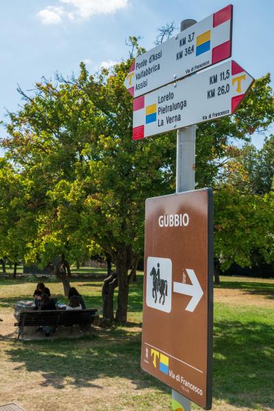 Via di Francesco signposts in Gubbio showing directions and distances to Assisi and La Verna.