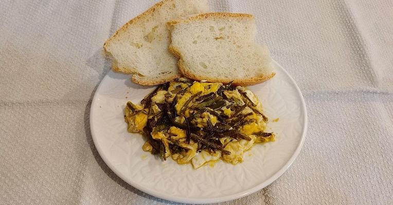Plate of golden elderflower fritters dusted with powdered sugar, on a rustic table with fresh elderflower blossoms.